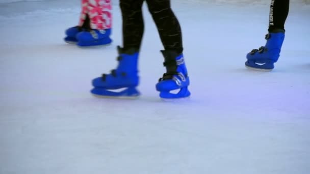 Close-up em crianças aprendendo patinação no gelo na pista de gelo artificial. Fechar-se em patins em pés que se movem em círculos
. - Filmagem, Vídeo