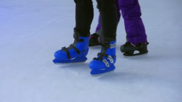 Closeup on kids feet wearing skating shoes while learning ice skating. - Footage, Video