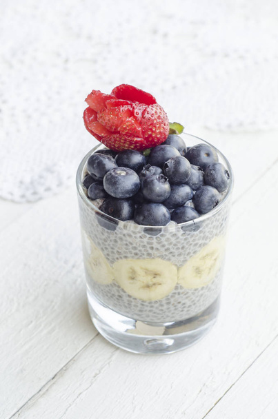 Homemade cold and sweet dessert with fresh fruits toppings. Chia seeds pudding. Healthy, delicious and high in dietary fiber. Rose flower bud carved from fresh strawberry - Φωτογραφία, εικόνα