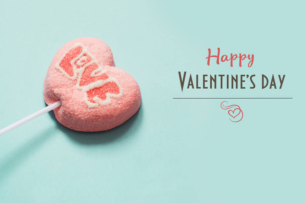 Lollipops pink candy on stick with Love text on blue background. Valentine's card. - Φωτογραφία, εικόνα