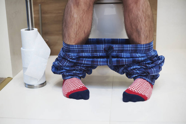 Low section of man defecating in the bathroom - Photo, Image