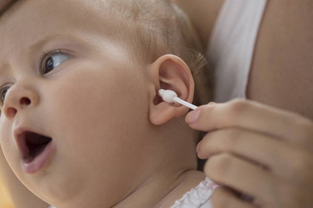 mother cleaning babies ear with cotton swabs - Photo, Image