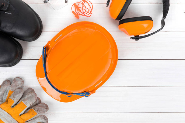 Banner image of construction safety gear including a hard hat,  safety shose ,goggles, and leather gloves flat lay on white wooden surface with copy space - Image - Φωτογραφία, εικόνα
