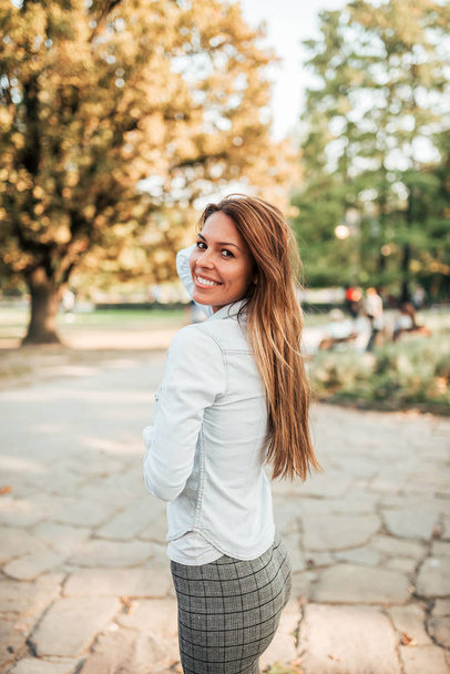 Portrait of a beautiful young woman in the park. Looking at camera. - Fotografie, Obrázek