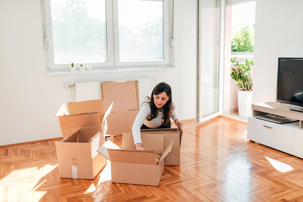 Young woman unpacking cardboard boxes at new home. - Photo, Image