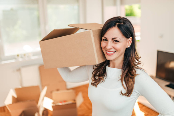 Moving concept. Close-up image of cheerful young woman holding cardboard box. - Фото, зображення