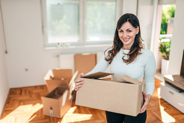 Moving to a new place. Young woman with carton box looking at camera. - Fotoğraf, Görsel