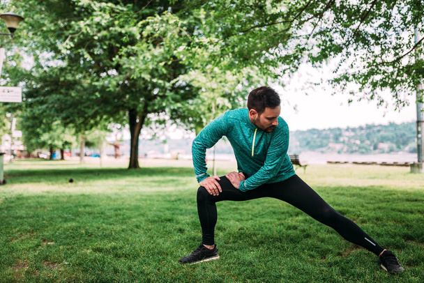 Fit man doing stretching exercises outdoors - Fotografie, Obrázek