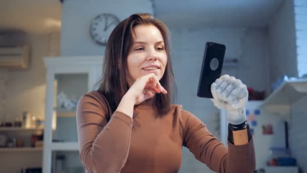 Smiling lady with a prosthetic hand is having a videocall - Felvétel, videó