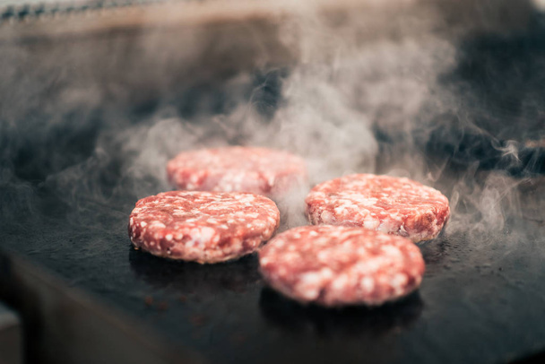  Close-up image of raw meat burgers on a grill. - Zdjęcie, obraz