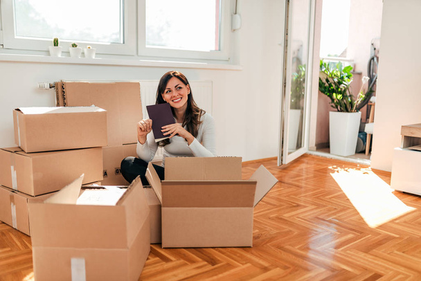 Smiling young woman moving. Looking through things while packing. - 写真・画像