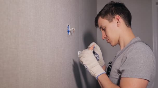 A férfi telepítése villanykapcsolót, szürke falon modern apartmanban tatarozás oldalnézete - Felvétel, videó