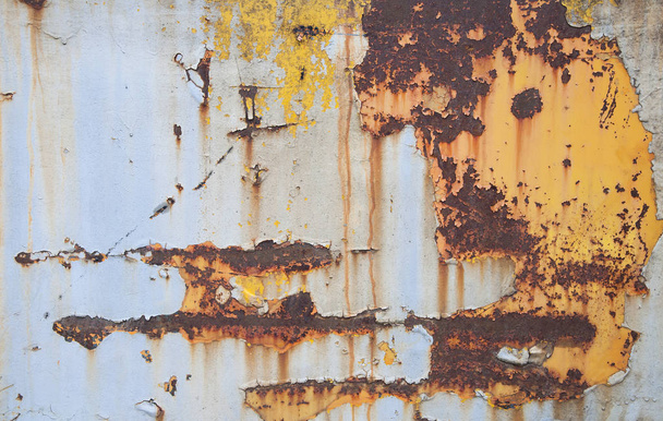 Παλιά σκουριά σχετικά με το σίδερο. Ραγισμένα χρώμα και γρατσουνιές, σε φόντο κίτρινο-μπλε μεταλλικό. - Φωτογραφία, εικόνα
