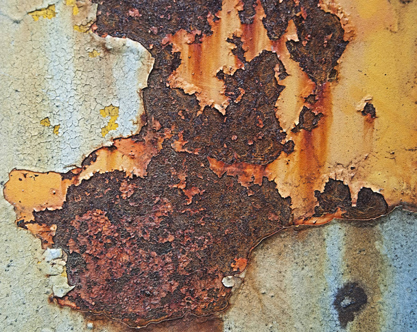 Old rust on the iron. Cracked paint and scratches, on a yellow-bluish metal background. - Photo, Image