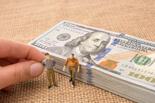 Mužské figurky nalezené vedle svazku bankovek v amerických dolarech - Fotografie, Obrázek