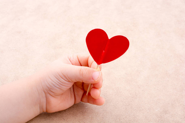 Λίγο κόκκινο χρώμα σχήμα καρδιάς στην κορυφή του ένα ραβδί στο χέρι - Φωτογραφία, εικόνα