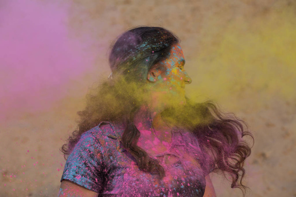 Meravigliosa modella bruna che si gode il festival Holi nel deserto. Donna in posa con esplodere vernice rosa
 - Foto, immagini