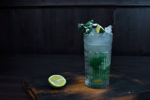 Pyszne piękne alkoholowe cocktail "Mojito" stanąć na boardzie vintage na drewnianym stole w nocnym klubie. - Zdjęcie, obraz
