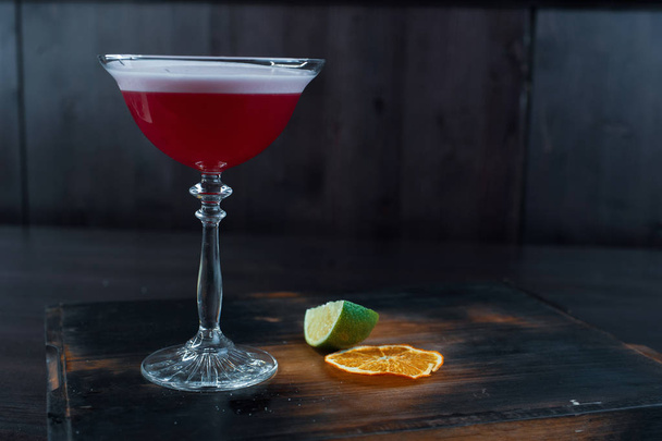 Mansikka kaksikerroksinen herkullinen cocktail tonicilla ja vodka marjaliköörillä kristallilasissa seisoo puulaudalla vintage-pöydällä ravintolassa. Viikonloppu yökerhossa
. - Valokuva, kuva