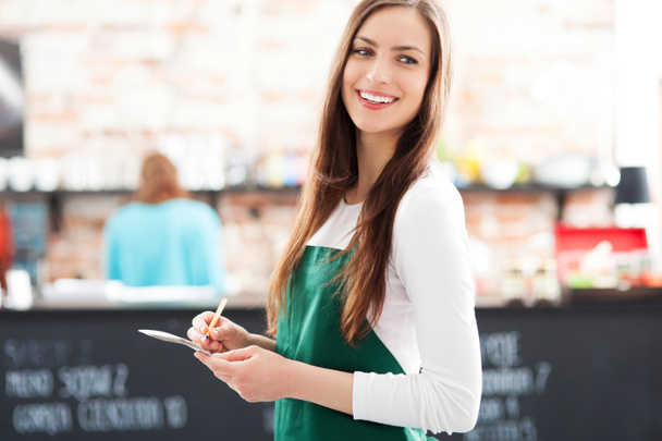 Молодая официантка держит блокнот в кафе
 - Фото, изображение