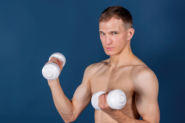 Closeup of a muscular young man lifting dumbbells - Foto, Bild