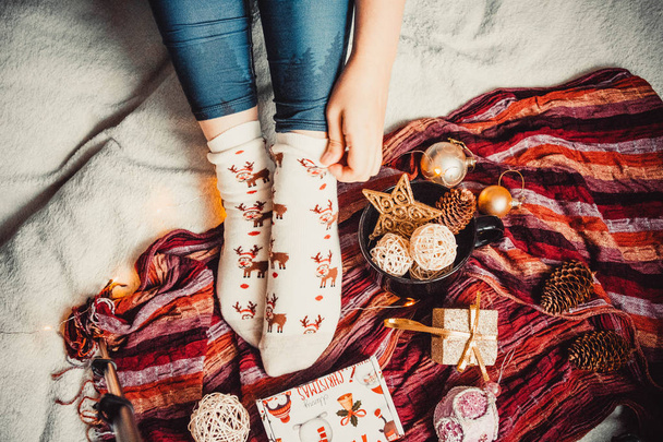 Gambe femminili sullo sfondo di un plaid accogliente e caldo e decorazioni natalizie - Foto, immagini