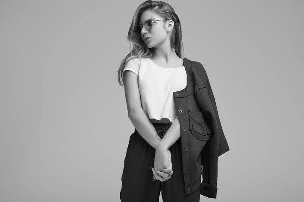 Retrato de menina adolescente bonito na jaqueta de moda e óculos de cor posando no fundo cinza. Estúdio
. - Foto, Imagem