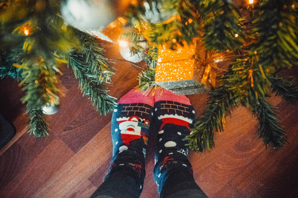 Female legs on the background of a christmas tree and decorations - Photo, Image