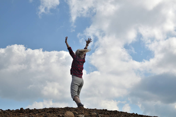 Счастливая женщина, одетая в королевского стюарда, прыгает по голубому небу с белыми облаками
 - Фото, изображение