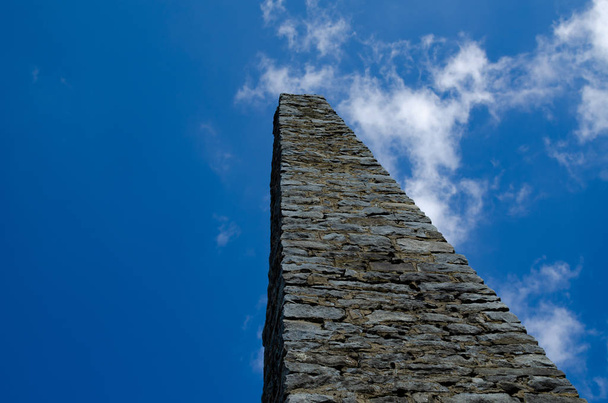 Kamenný obelisk proti modré obloze s cloudem - Fotografie, Obrázek
