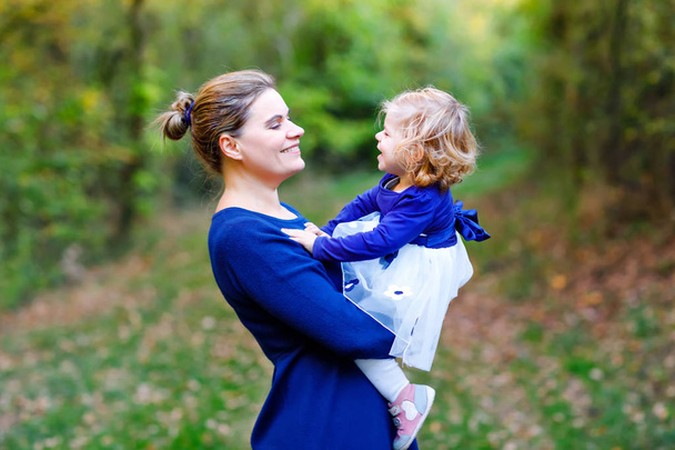 Happy young mother having fun cute toddler daughter, family portrait together. Woman with beautiful baby girl in nature and forest. Mum with little child outdoors, hugging. Love, bonding. - Photo, Image