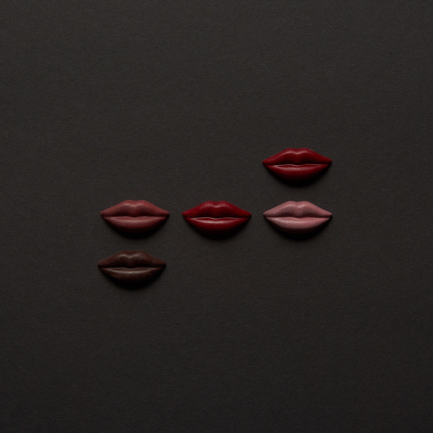 top view of sweet multicolored chocolate lips on black background  - Photo, Image