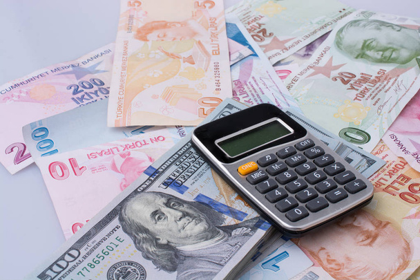 Számológép, amerikai dollár-bankjegyek és Turksh líra bankjegyeit egymás mellett a fehér háttér - Fotó, kép