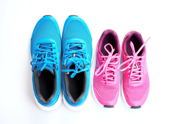 Paar blaue Laufschuhe für Männer und pinkfarbene für Frauen auf weißem Hintergrund. Konzept Love Run. Gemeinsam laufen. Familienbetrieb. Ansicht von oben. - Foto, Bild