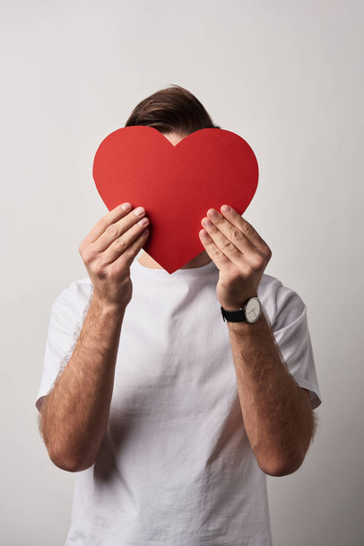 man with obscure face holding empty red paper cut heart card  - 写真・画像