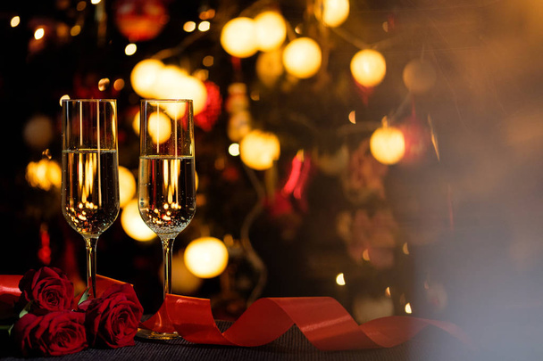 Glasses of champagne on the background of lights with roses and red ribbon - Foto, Imagem