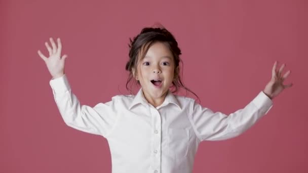 cute little child girl in white shirt shows different emotions on pink background. - Footage, Video
