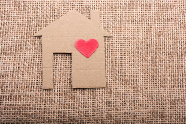 Форма сердца на форме дома вырезанная из бумаги на фоне холста - Фото, изображение