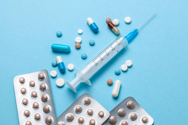 Birth control pills, an injection syringe on blue background - Photo, Image