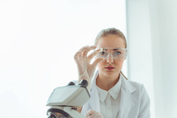 Επιστήμονας έρευνας εργαστήριο στην ασφαλή γυαλιά χρησιμοποιώντας μικροσκόπιο για την ανάλυση αντι βακτηρίδια μέσω διαφανειών γυαλιού, τεχνολογία της βιοτεχνολογίας, επιστήμη, χημεία., επαγγελματίες υγειονομικής περίθαλψης και της ιατρικής - Φωτογραφία, εικόνα