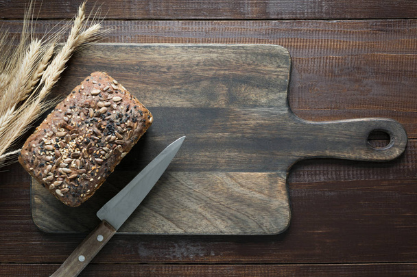Loaf of fitness rye bread with ears of wheat on wooden board. Close up. Space for text. - 写真・画像