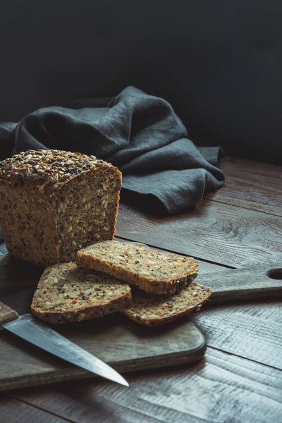 Loaf of fitness rye bread with ears of wheat on wooden board. Close up. Space for text. - Foto, afbeelding