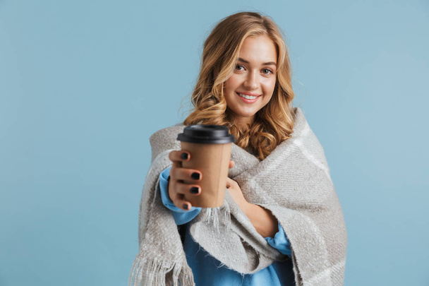 Image of european woman 20s wrapped in blanket holding takeaway coffee isolated over blue background - Photo, Image