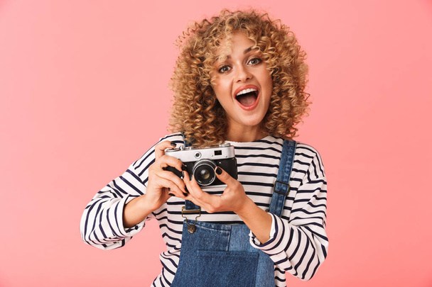 幸せ中女性 20 代 photopraphing ピンク背景に分離立ちながらレトロなカメラでの写真 - 写真・画像