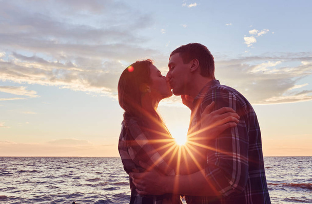 Couple of lovers kissing into water at sunset - Romantic scene of multiethnic couple - Photo, Image