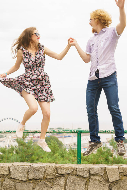Joyful couple having fun outdoor. Young man and woman dancing jumping together during date. - 写真・画像