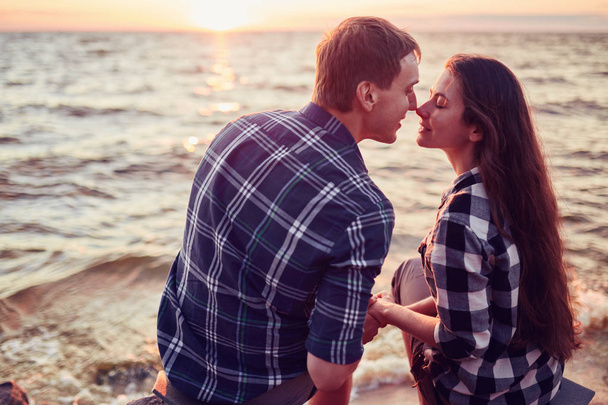 Pár csók vízbe a naplemente - romantikus táj a többnemzetiségű pár szerelmesek - Fotó, kép