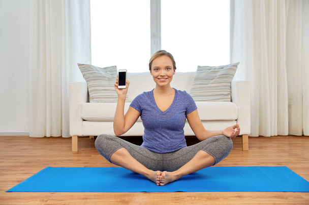 woman with smartphone doing yoga at home - Φωτογραφία, εικόνα