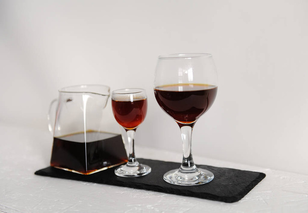 試飲のための 2 つのワイングラスの透明なサービング ティーポットにコーヒー。白い背景の上のスレート ボードで提供しています. - 写真・画像