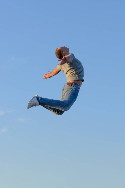young man in a jump against a blue sky - Fotó, kép